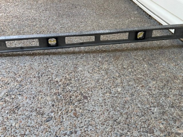 Level showing a 2-inch reverse slope on a front porch