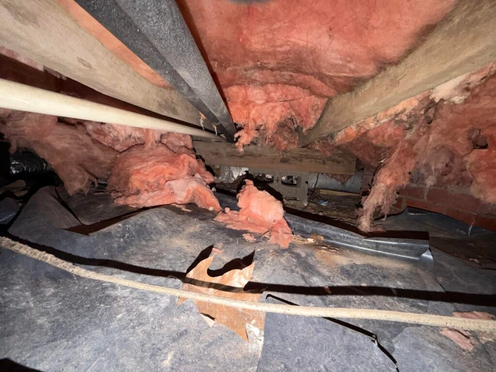 Concrete block laid on its side as improper floor support in a crawlspace